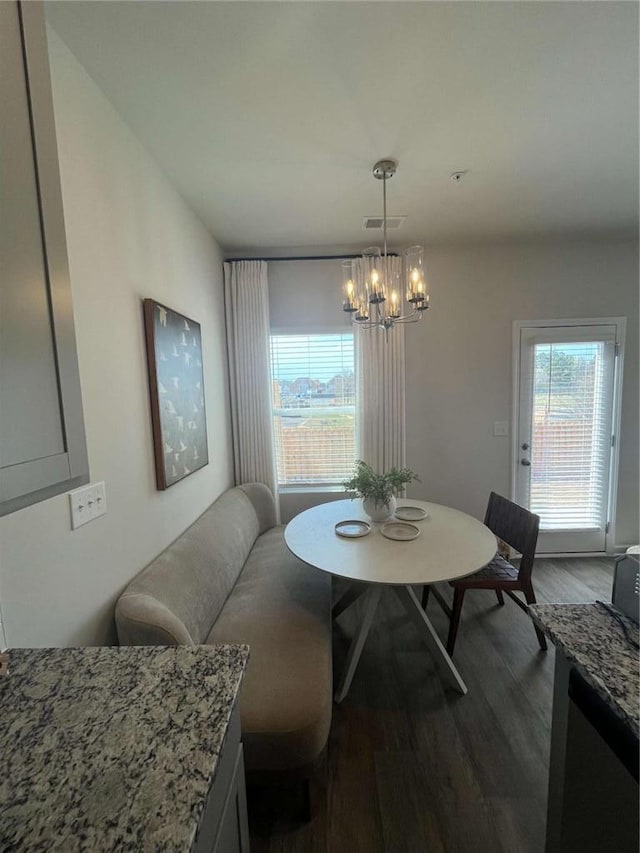 dining area featuring dark wood-style flooring, visible vents, and a notable chandelier