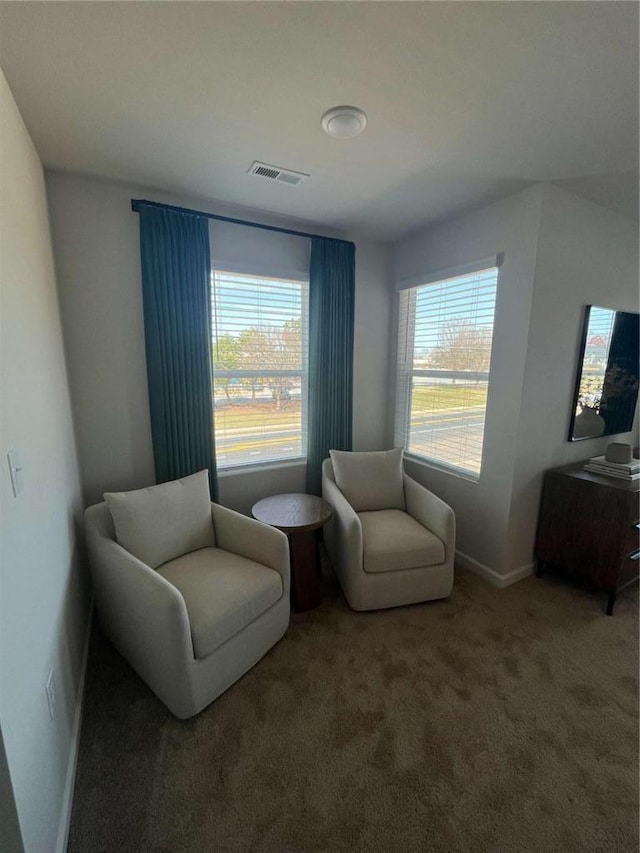 living area with carpet floors, plenty of natural light, visible vents, and baseboards