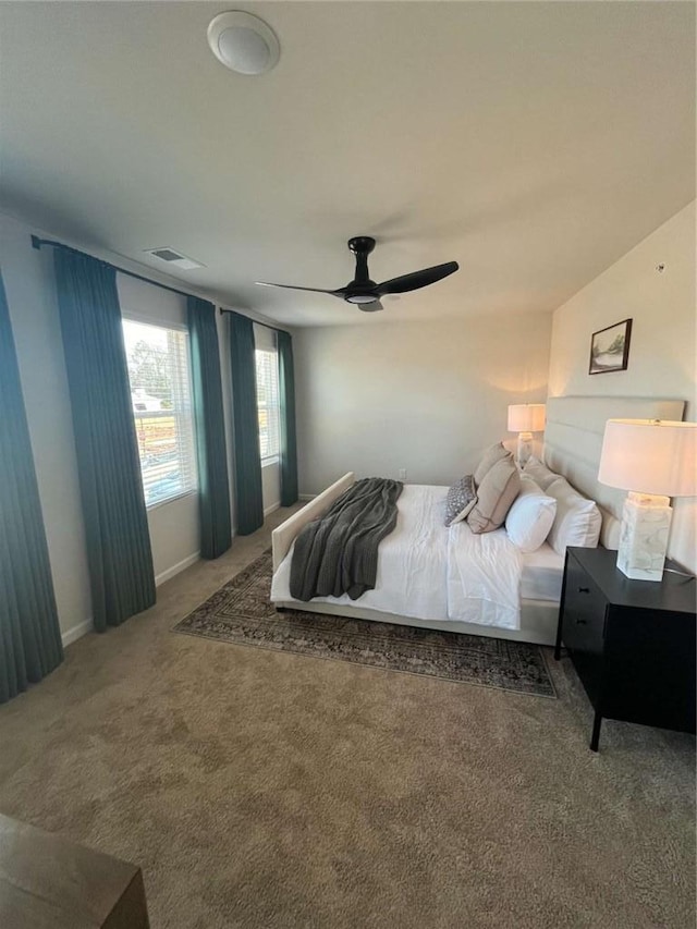 carpeted bedroom featuring baseboards, visible vents, and a ceiling fan