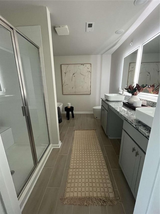 bathroom with double vanity, visible vents, toilet, a shower stall, and a sink