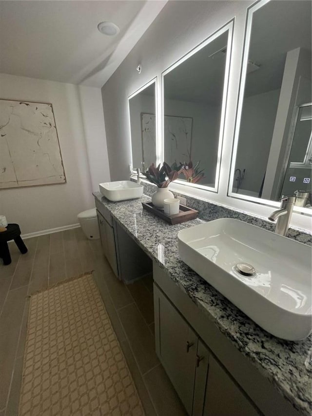 bathroom featuring lofted ceiling, double vanity, a sink, and toilet