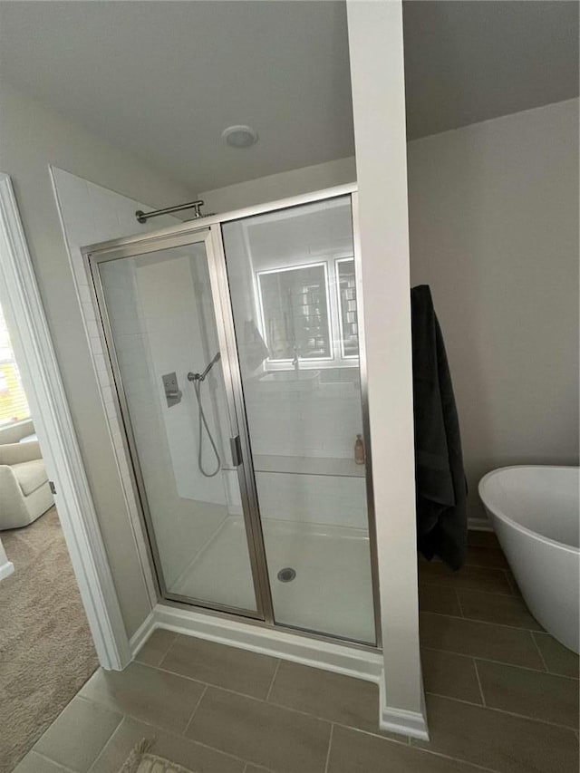 bathroom with tile patterned flooring, a freestanding bath, and a shower stall