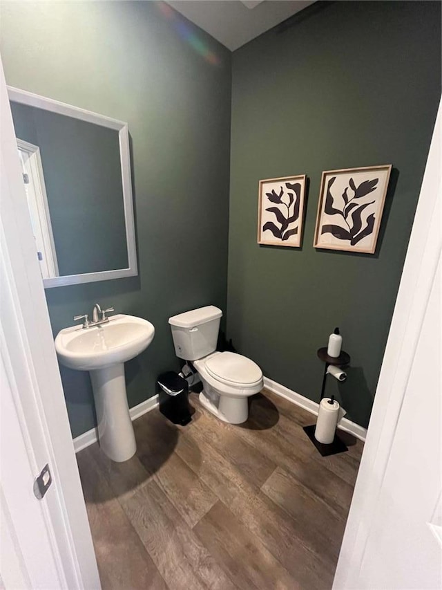 bathroom with a sink, wood finished floors, toilet, and baseboards