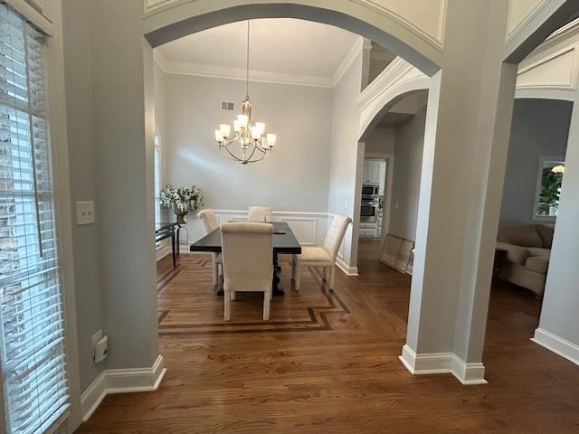 dining space with ornamental molding, baseboards, a chandelier, arched walkways, and dark wood finished floors