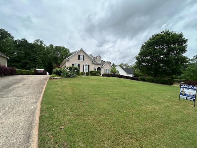 view of front of property featuring concrete driveway and a front lawn