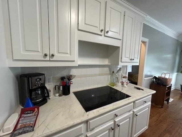 kitchen with decorative backsplash, black electric stovetop, and white cabinets