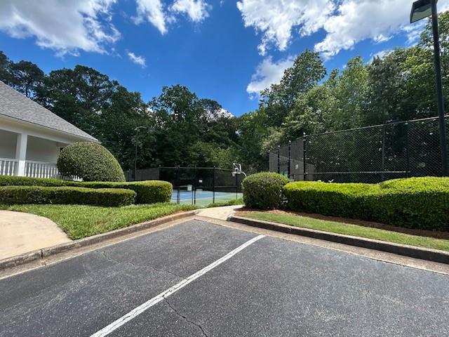 uncovered parking lot featuring fence and a tennis court