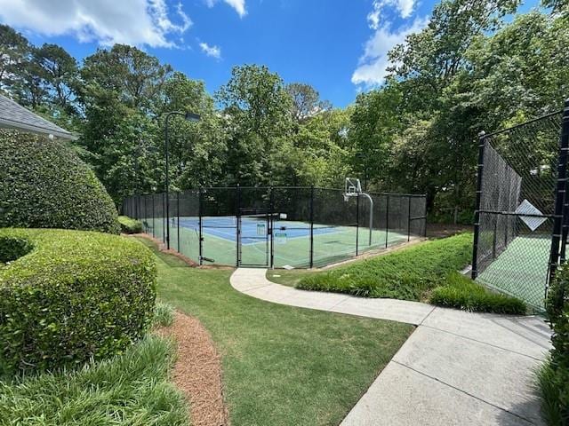 view of sport court featuring a lawn, fence, and community basketball court
