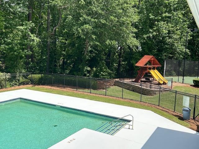 view of pool with a lawn, a fenced in pool, playground community, and fence