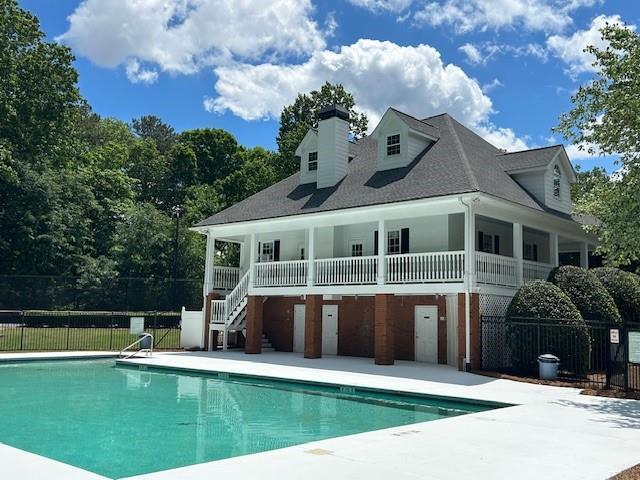 rear view of house featuring a chimney, fence, a patio area, a community pool, and stairway