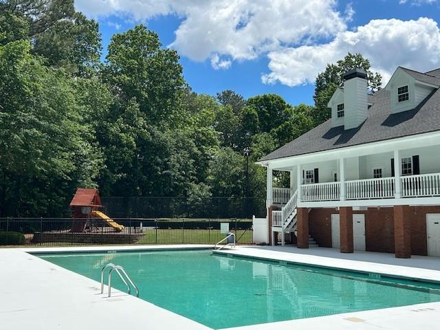 pool with fence, a patio, playground community, and stairs