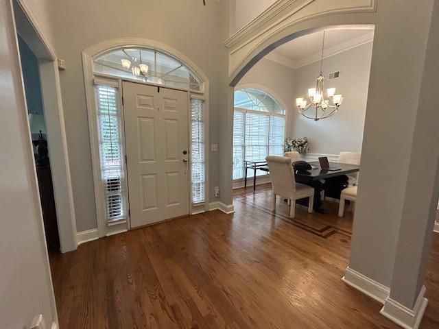foyer with a healthy amount of sunlight, wood finished floors, and a chandelier