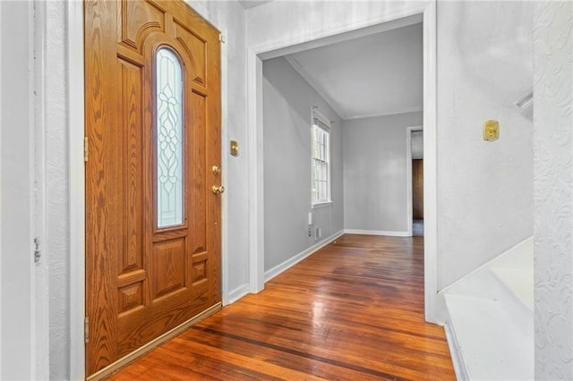 entryway with crown molding and dark wood-type flooring