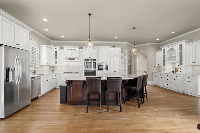 kitchen with a kitchen island, glass insert cabinets, hanging light fixtures, stainless steel appliances, and white cabinetry