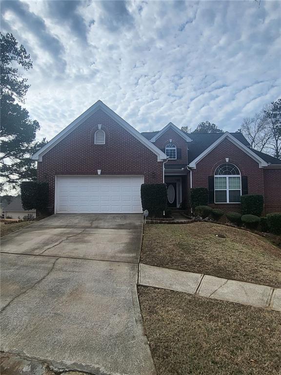 view of front of home with brick siding, an attached garage, and driveway