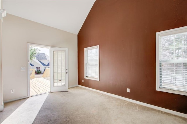 unfurnished room with light colored carpet, baseboards, and high vaulted ceiling