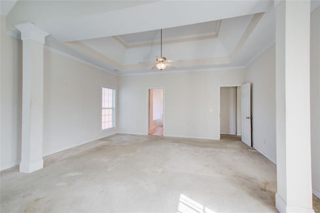 empty room featuring ceiling fan, ornamental molding, light carpet, a raised ceiling, and ornate columns