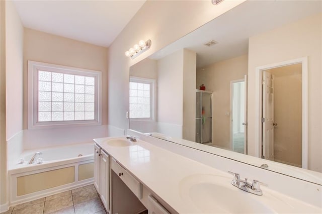 bathroom with tile patterned floors, a bath, double vanity, and a sink