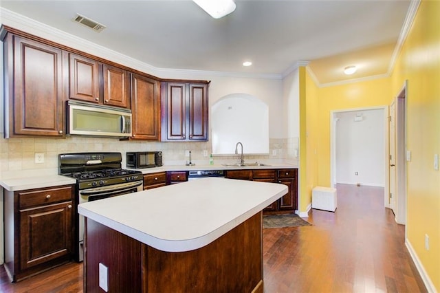 kitchen with a sink, dark wood finished floors, stainless steel appliances, light countertops, and decorative backsplash