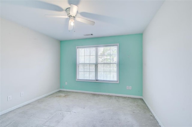 carpeted spare room with baseboards, visible vents, and ceiling fan