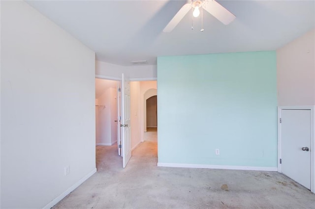 empty room with a ceiling fan, visible vents, baseboards, arched walkways, and concrete flooring