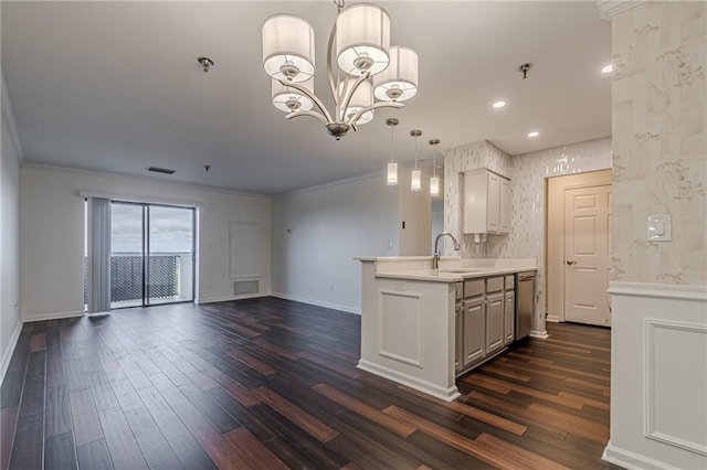 kitchen featuring kitchen peninsula, dark hardwood / wood-style flooring, ornamental molding, sink, and pendant lighting