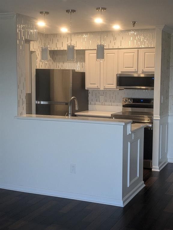 kitchen featuring dark hardwood / wood-style floors, white cabinetry, stainless steel appliances, and kitchen peninsula