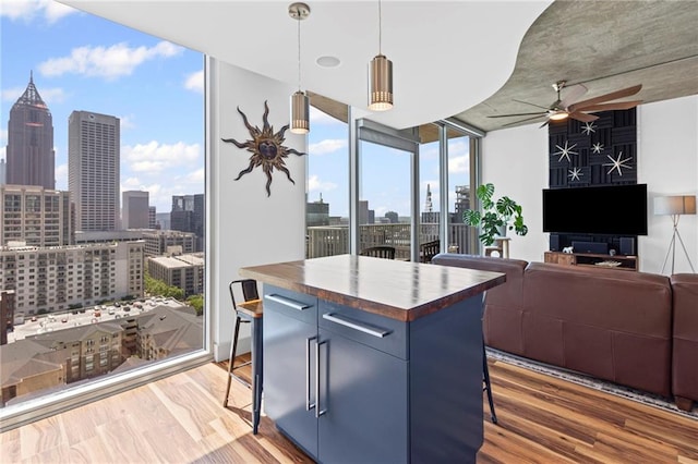 kitchen featuring expansive windows, a ceiling fan, butcher block counters, a skyline view, and a breakfast bar