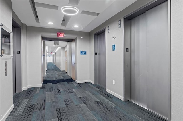hallway with elevator, dark carpet, and baseboards