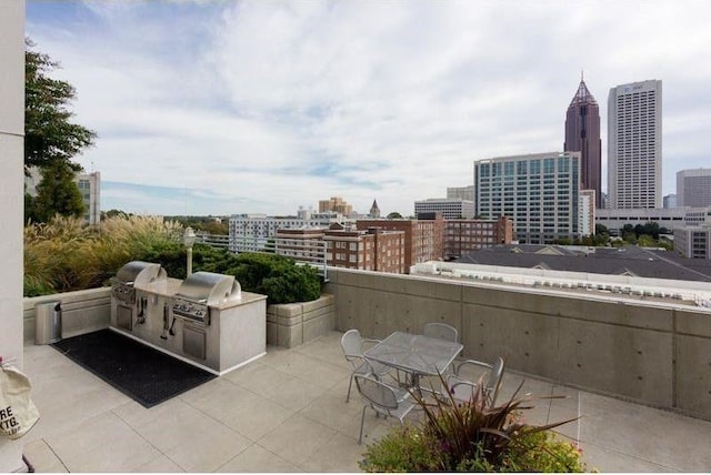 view of patio / terrace with a grill, a skyline view, exterior kitchen, and outdoor dining space