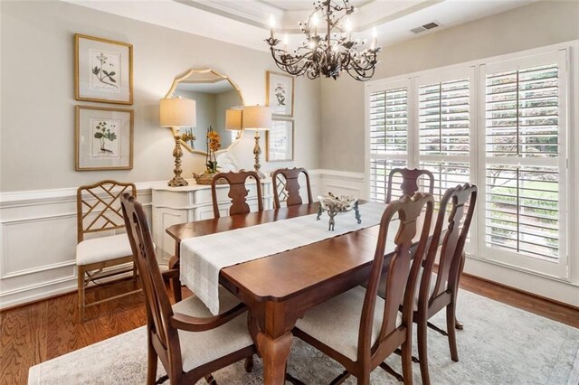 4401 Madison Woods Dr NW, Marietta, GA 30064 - dining area featuring wood finished floors, a chandelier, a raised ceiling, a decorative wall, and a wainscoted wall
