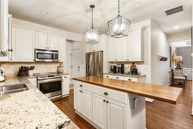 4401 Madison Woods Dr NW, Marietta, GA 30064 - kitchen featuring appliances with stainless steel finishes, butcher block countertops, a chandelier, decorative backsplash, and white cabinetry