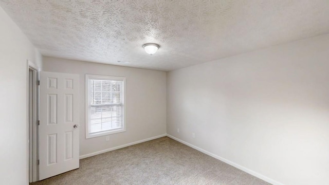 empty room featuring carpet, a textured ceiling, and baseboards