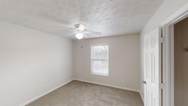 empty room featuring light carpet, ceiling fan, a textured ceiling, and baseboards