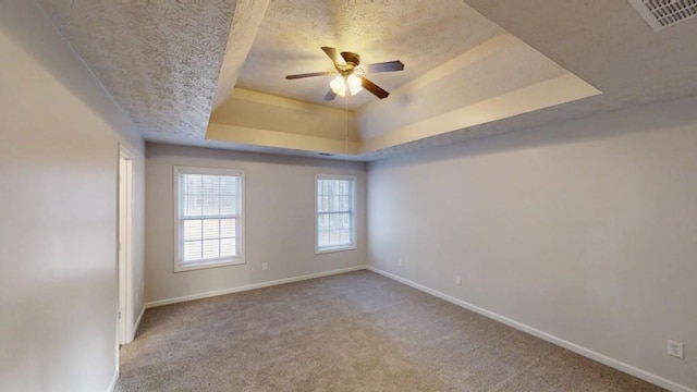 unfurnished room with a raised ceiling, carpet flooring, a textured ceiling, and baseboards