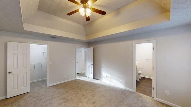 unfurnished bedroom with a tray ceiling, baseboards, visible vents, and carpet