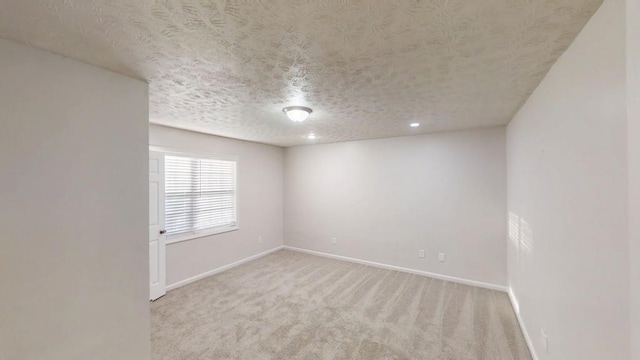 empty room featuring carpet flooring, a textured ceiling, and baseboards