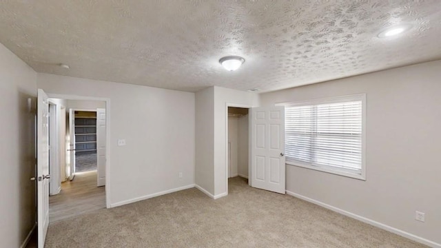 unfurnished bedroom featuring a closet, carpet flooring, a textured ceiling, and baseboards