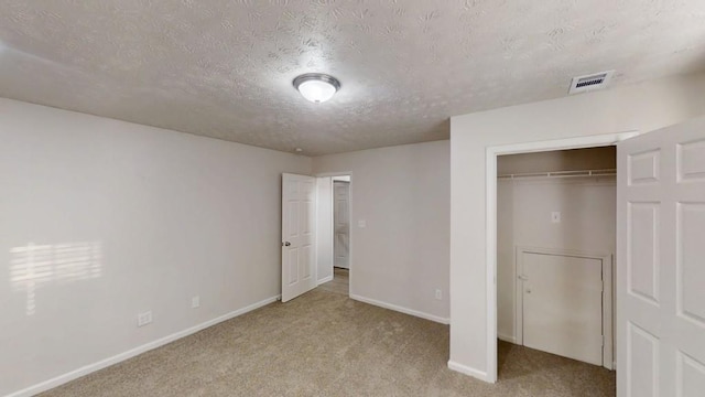 unfurnished bedroom with baseboards, visible vents, a textured ceiling, carpet flooring, and a closet