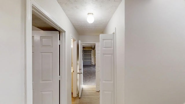 hallway featuring a textured ceiling and light wood-style flooring