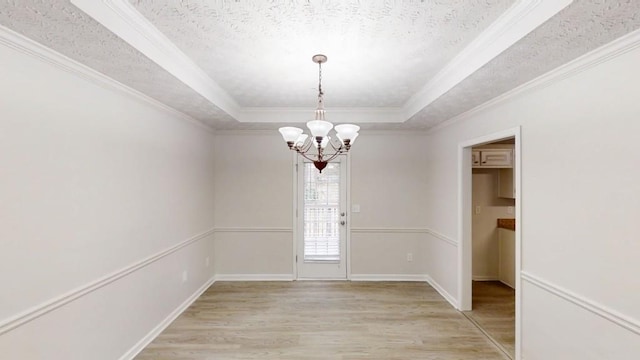 interior space featuring a textured ceiling, a raised ceiling, light wood-style flooring, and a notable chandelier