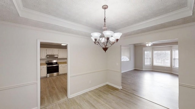 empty room with a textured ceiling, crown molding, a raised ceiling, and light wood-style floors