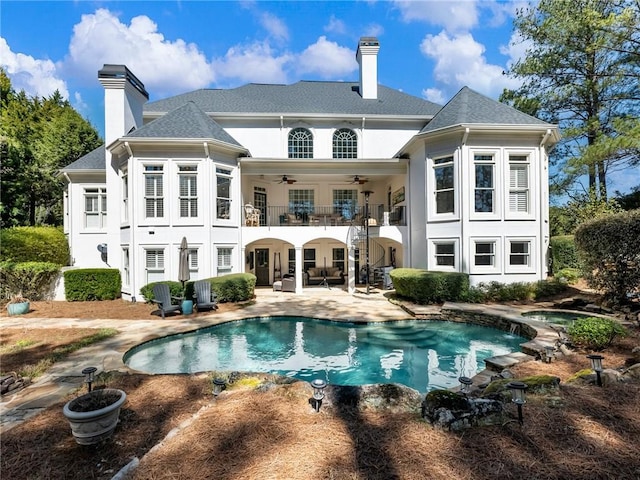 back of house featuring a patio, a ceiling fan, a balcony, and a chimney