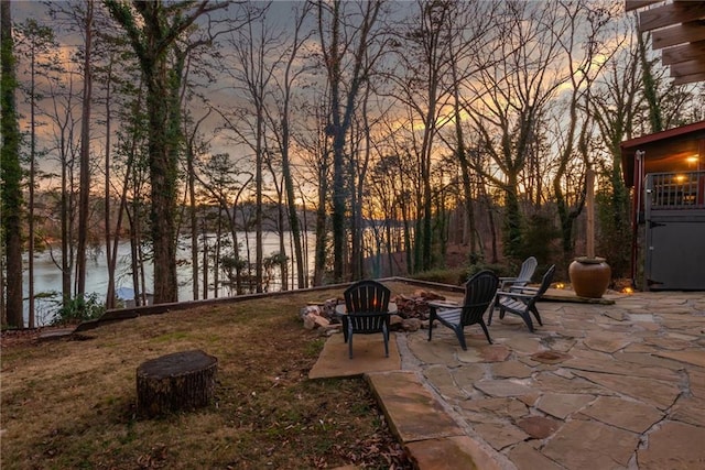 patio terrace at dusk featuring an outdoor fire pit and a water view