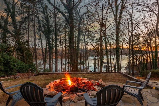 patio terrace at dusk with a water view and an outdoor fire pit