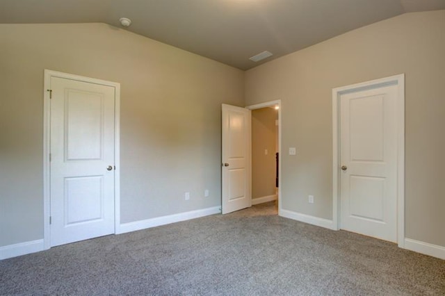 unfurnished bedroom featuring light carpet and lofted ceiling