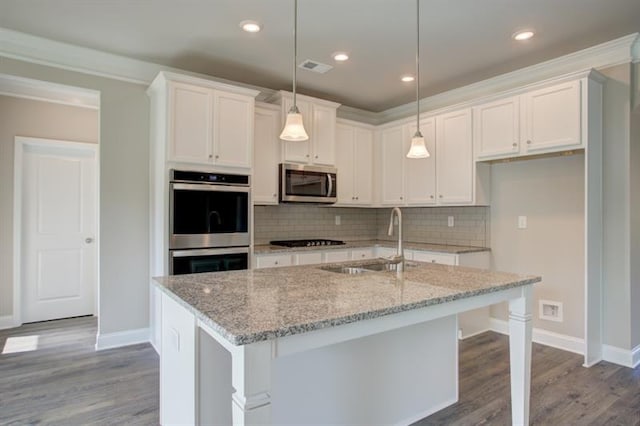 kitchen featuring a kitchen island with sink, light stone countertops, sink, appliances with stainless steel finishes, and white cabinets