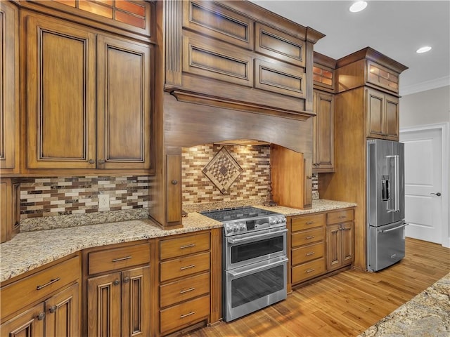 702 Cash Rd NE, Calhoun, GA 30701 - kitchen with stainless steel appliances, light wood finished floors, backsplash, brown cabinetry, and ornamental molding
