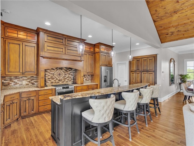 702 Cash Rd NE, Calhoun, GA 30701 - kitchen with stainless steel appliances, brown cabinetry, light wood-type flooring, a spacious island, and a kitchen bar