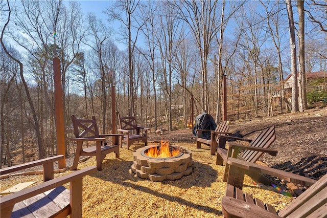 view of yard featuring an outdoor fire pit and a view of trees